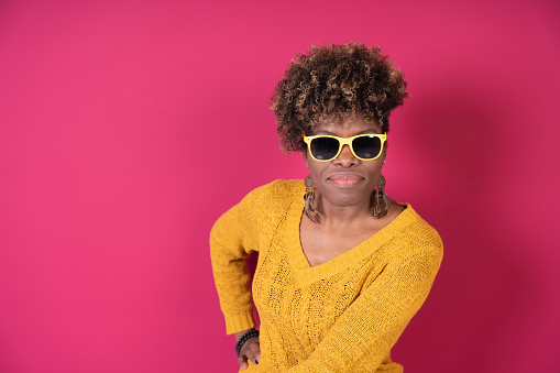 A trendy woman stands confidently with her hands on her hips, sporting a bright yellow knit sweater and stylish yellow sunglasses. copy space.