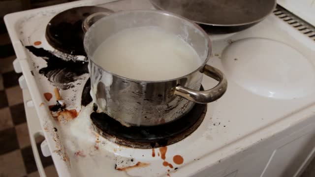 dirty old stove with boiling milk