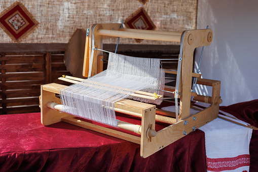 A closeup image of an old weaving Loom and thread of yarn