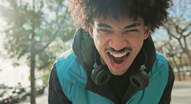 Young Black man approaching camera, laughing and shouting
