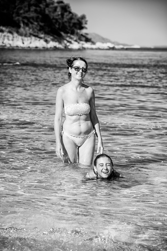 Family. Vacation. A family swims near the shore. Mother and daughter smiling.
