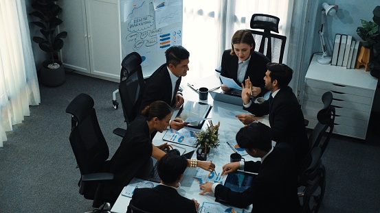 Top view of smart businesspeople working together at meeting. Manager looking at financial document while making decision to invest in stock market. Business people analyze business data. Directorate.