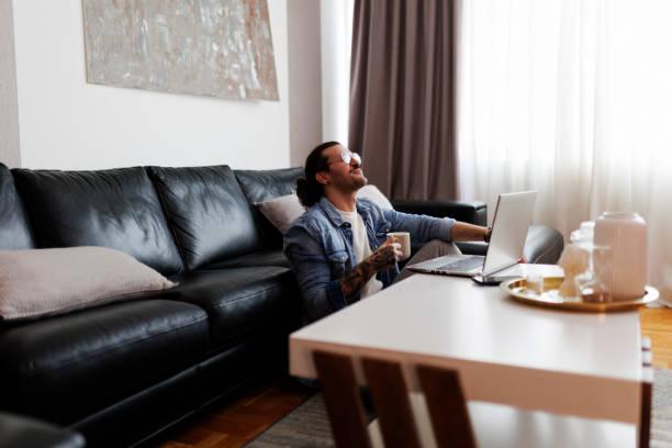 istock Businessman drinking coffee and using laptop while working at home 2084180715