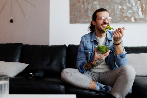 Man eating salad and drinking water at home