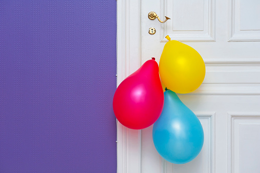 White wooden door decorated with three colorful balloons