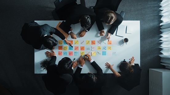 Top down aerial view of manager discuss and choose marketing idea from sticky notes. Group of business team talking and brainstorming strategy while making decision and choose plan. Directorate.