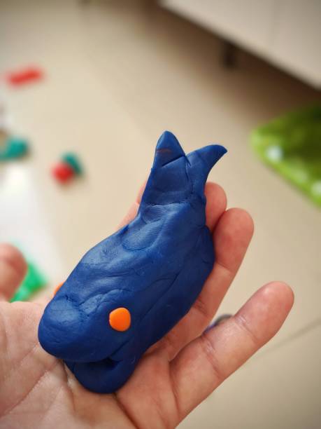 A whale made of play dough. Child playing. Human hand