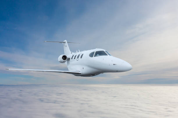 istock White private jet fly in the air above the clouds 2084268192