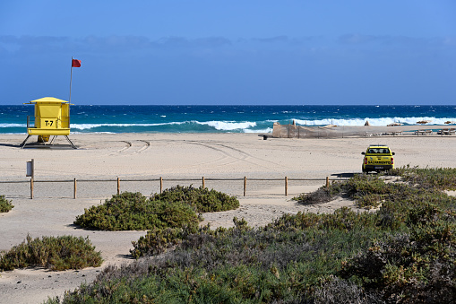 Red flag on an empty beach meaning swimming not allowed due to large waves and rough conditions at Playa de Maspalomas, popular resort in the south of the island of Gran Canaria, Canary Islands, Spain.