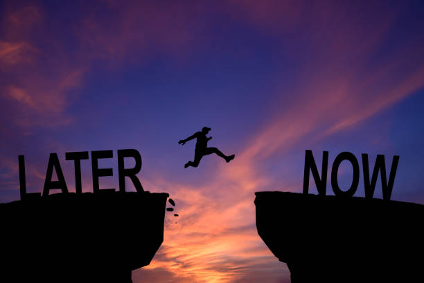 istock Man jump through the gap between Later to Now on sunset. Concept. 2084310372