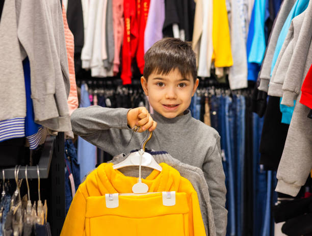 istock happy kid choosing clothes in shopping mall. 2084314072
