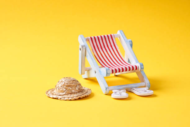 Red miniature wooden deck chair at the shoreline of Pedn Vounder Beach, South Cornwall on a sunny June day.