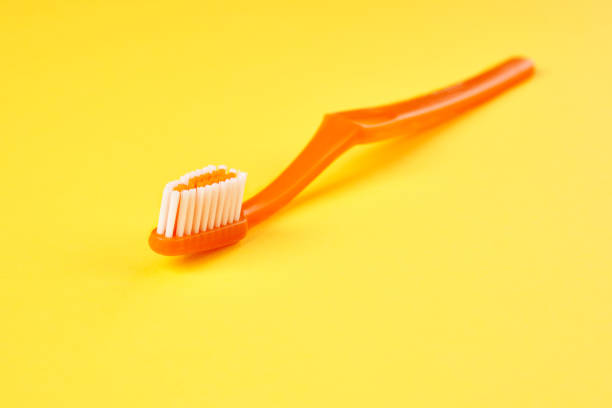 Toothbrush on yellow background close up.