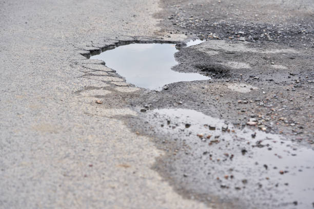 istock Pit on asphalt road filled with water. 2084360195