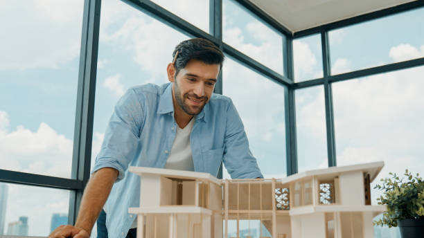istock Portrait of engineer smiling at camera while inspect house model. Tracery 2084363649