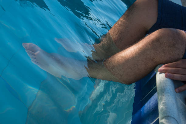 Man leaving legs in water pool in hot day at summer
