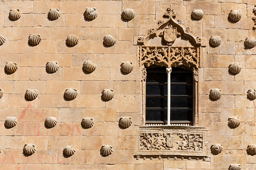 Casa de las Conchas in Salamanca, Spain, facade decorated with shell carvings, gothic style, window with coat of arms.