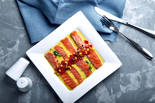 Slice of salmon with pepper, seasalt, herbs and olive oil. Top view, space for text