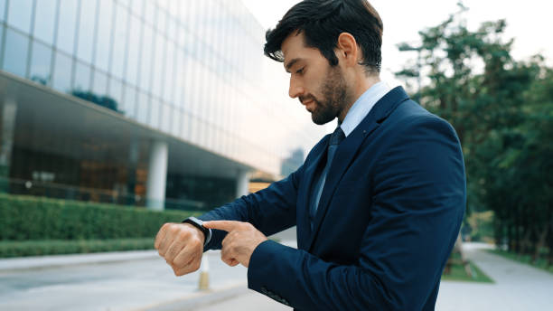 istock Caucasian business man looking at time while standing at building. Exultant. 2084421159