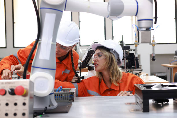 istock Women robotics engineers team working on project research, examining a robot arm prototype and programming it. 2084422271