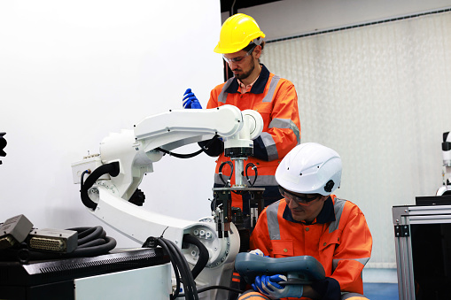 colleagues Mechanical Engineers test programs and simulation robots arm in industrial laboratories.