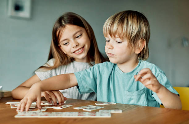 child girl boy childhood kid brother sister game card logic find quiz sorting education learning game puzzle attention board game Portrait of brother and sister having fun together playing game of cards matching logic or board game at home discover card stock pictures, royalty-free photos & images