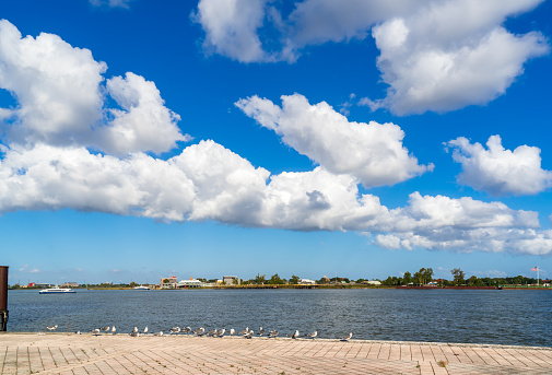 Background of beautiful white cloud and blue sky over the Mississippi River. The opposite is Algiers Point. The New Orleans Riverfront or the French Quarter River Walk is a nice spot to promenade the parks, plazas, parking lot, facilities.