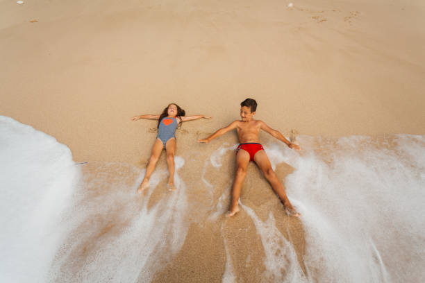 Child toddler standing hesitated on beach in front of sea and going to swim concept for children overcoming fear water