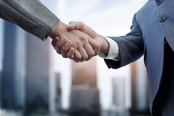 istock Two businessmen are shaking hands with each other . 2084450393