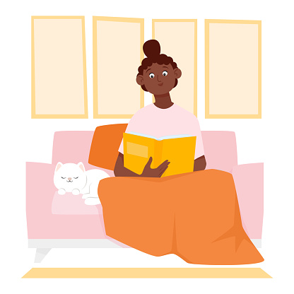 Cute young black woman sitting on the sofa and reading a book
