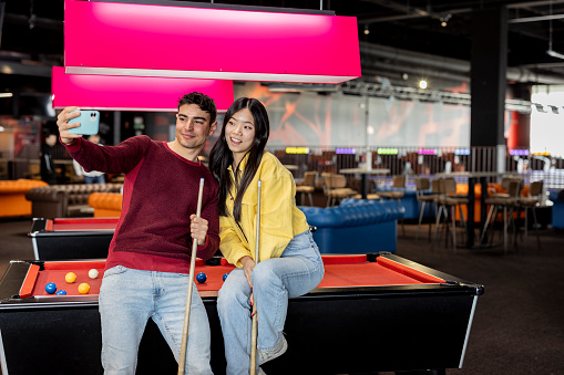 multiracial couple on a date making a selfie at the billiards in the recreational park