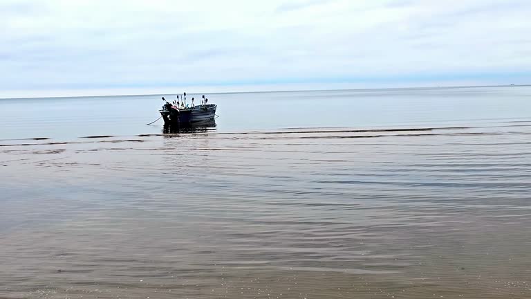 A fisherman boat is floating in the ocean without people on it. The water is calm and the sky is cloudy