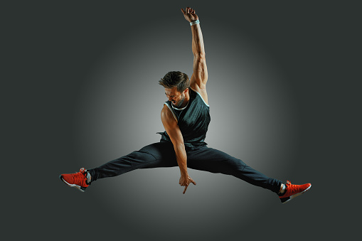 joyful athletic build man jumping on air on a black background. Lifestyle and sport concept.