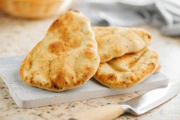 istock Freshly Baked Naan Bread on citting board on kitchen table. 2084523576