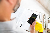 Construction Workers using a smartphone with blueprints and tools in the background