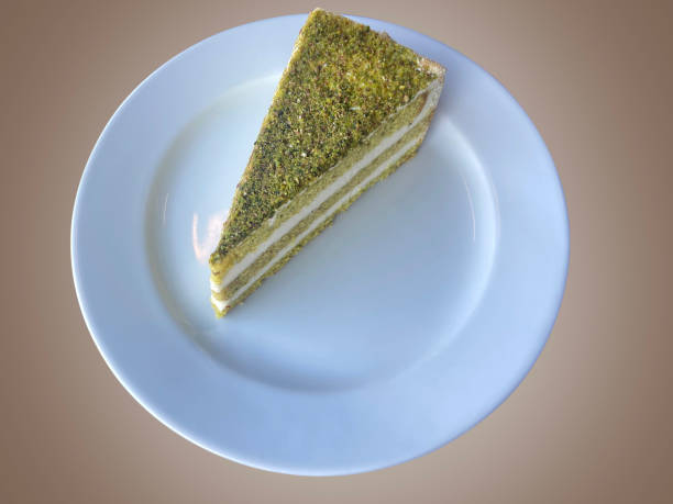 A slice of pistachio cake in a white plate isolated on pastel colored background with clipping path