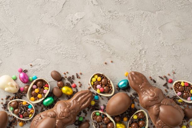 istock Modern Easter candy presentation. A top-down view of broken chocolate eggs with a bounty of colorful sweets, a chocolate bunnies, and sprinkles on a textured grey backdrop with ample space for text 2084539545
