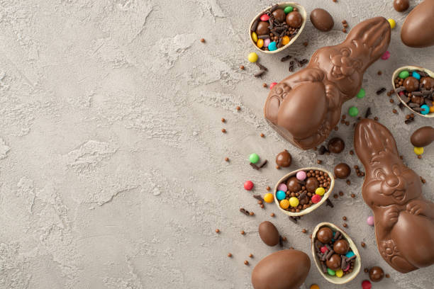 istock Luxurious contemporary Easter treats display. Overhead shot showing broken chocolate eggs brimming with vibrant sweets, milk chocolate rabbits, and sprinkles on a sleek slate backdrop, space for copy 2084539883