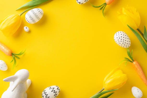 istock Easter creativity concept. Top view of minimalistic colored eggs, adorable hare statuette, carrots as treats for Easter Bunny, and tulips on a vivid yellow background with space for text or advert 2084539921