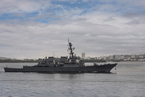 Cartagena, Colombia - July 25, 2023: USS Cole DDG-67 Arleigh Burke-class USA navy destroyer sails into port on Bahia de Cartagenas under gray morning cloudscape with blue patches