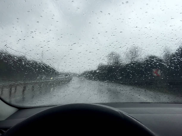 istock Driving on rainy day. Raindrops on windshield with road background 2084576634