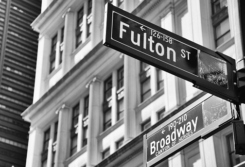 New York City, NY / USA - September 2012: The top of the Flatiron building with a Broadway sign in the foreground. Black and white.