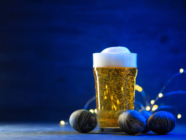 istock A glass of light beer on the table and painted Easter eggs. Blue background and copy space 2084644528