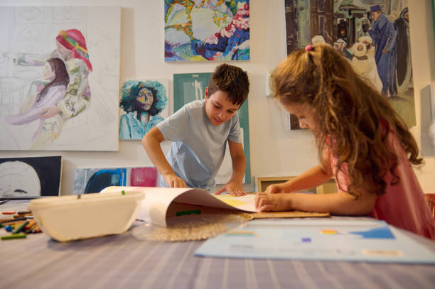 美術学校やギャラリーのビジュアルアートのクラスで絵を描いたり、壁にアート作品を飾ったりする多様な子供たち - child art childs drawing painted image ストックフォトと画像