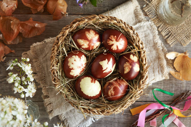 istock Brown Easter eggs dyed with onion skins in a basket with spring flowers, top view 2084671406