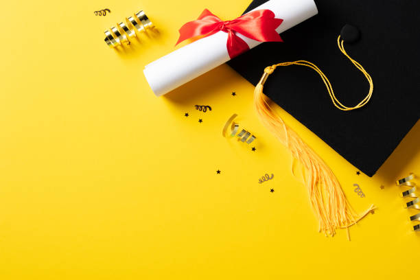istock Flat lay composition with graduation hat, students diploma, gold tinsel on yellow background. Graduation party concept. 2084672468
