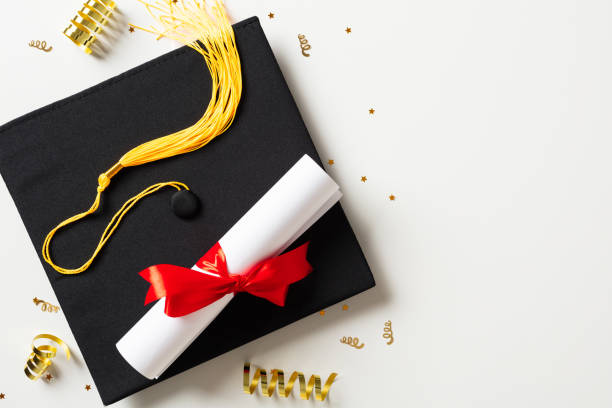 istock Graduation party concept. Flat lay square academic cap with diploma and gold tinsel on white background. 2084677698