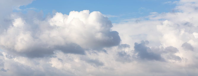 Billowing clouds float in a vast blue sky, showcasing the dynamic and airy dance of weather. Banner. Atmosphere background or wallpaper