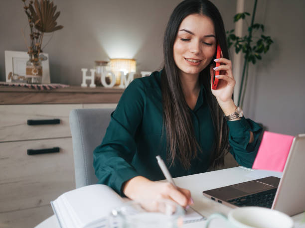 istock Young smiling woman sitting at home and using laptop computer. 2084728929