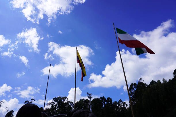 Flags of Colombia and Italy waving on a blue-sky background.